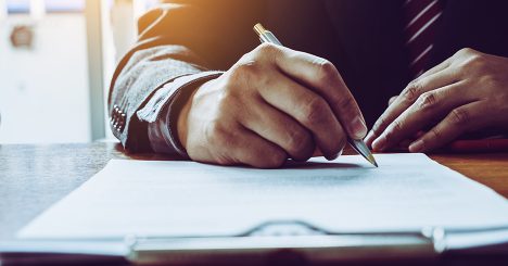 Hands Signing Document With Pen