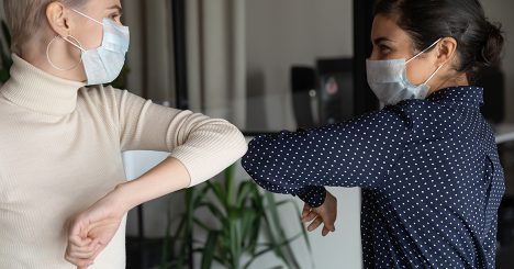 Women In Masks Bumping Elbows Together