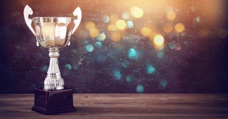 Gold Trophy On Wooden Table With Gold And Blue Glitter