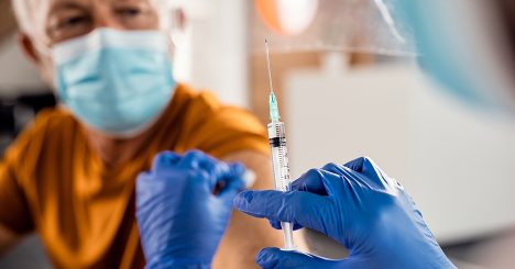 Nurse In Gloves Administering Vaccine Shot To Man