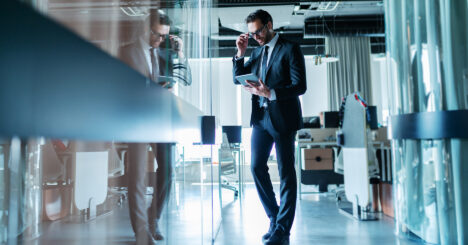 Business Man Standing In Front Of His Office And Using Tablet For Work