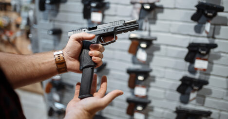 Man Choosing New Handgun In Gun Shop